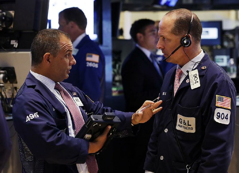 Traders Joel Lucchese (left) and Michael Urkonis confer Monday on the floor of the New York Stock Exchange. Stock indexes rose Monday as companies began reporting quarterly earnings. 