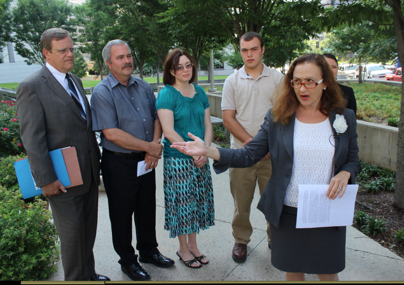 ACLU of Arkansas Executive Director Rita Sklar speaks at a news conference Tuesday in front of, from left to right, attorney Pat James, Ron Robinson, Eva Robinson, Matthew Robinson and ACLU Legal Director Holly Dickson.