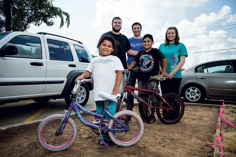 Crafton Tull is celebrating its 50th anniversary with 50 acts of kindness, including partnering with a construction company to build bike racks for City of Hope Outreach in Oakwood Village and Brookside Mobile Village in Conway. From the left are Noemi Trujillo, 7; Michael Kidd, Oakwood community director; Jared Bridgman, survey technician for Crafton Tull; Eric Trujillo, 9; and Brianna Kidd, director of the Oakwood Learning Academy.