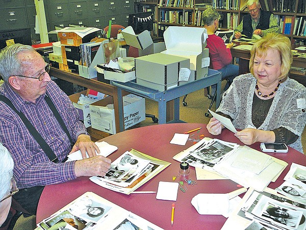 Tommy Kendrick and Margaret Johnson look over old photos at the Shiloh Museum of Ozark History in Springdale. The two are part of the Photo Identification Group, which meets once a month to identify people, places and events in photos taken in Northwest Arkansas in the mid- to late 20th century. 
