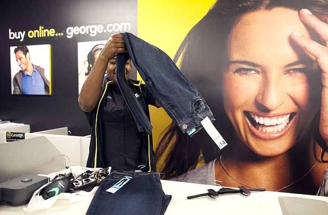 An employee at an Asda supermarket, the British retail arm of Wal-Mart Stores Inc., folds a pair of jeans at a London store that were manufactured in Bangladesh. A plan by Wal-Mart and other North American retailers to improve safety conditions in Bangladesh garment factories falls short of a similar plan adopted by mostly European retailers, critics say. 