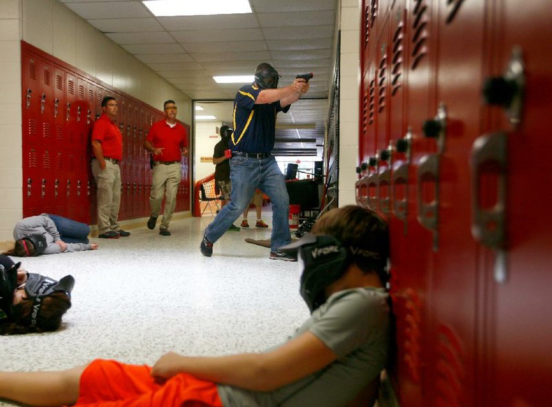 NWA Media/JASON IVESTER
Springdale Police Lt. Scott Lewis (from left) and Sgt. Robert Sanchez watch as Clarksville High School Assistant Principal Cheyne Dougan turns a corner into a classroom during an active shooter training on Thursday, July 11, 2013, inside Clarksville High School. Faculty members were going through training scenarios which involved actors playing the roles of students and active shooters inside the school.