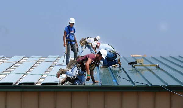 Construction crews work Friday on the roof of a building at 2713 SE Otis Corely Drive in Bentonville. The building will be the new home of Norwalk Juicers. The facility will double the space for Norwalk to about 20,000 square feet. 