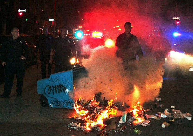 Oakland police officers work to extinguish a fire during a protest after George Zimmerman was found not guilty in the 2012 shooting death of teenager Trayvon Martin, early Sunday, July 14, 2013, in Oakland, Calif. Protesters angered by the acquittal Zimmerman held largely peaceful demonstrations in three California cities, but broke windows and started small street fires Oakland, police said. (AP Photo/Bay Area News Group, Anda Chu)