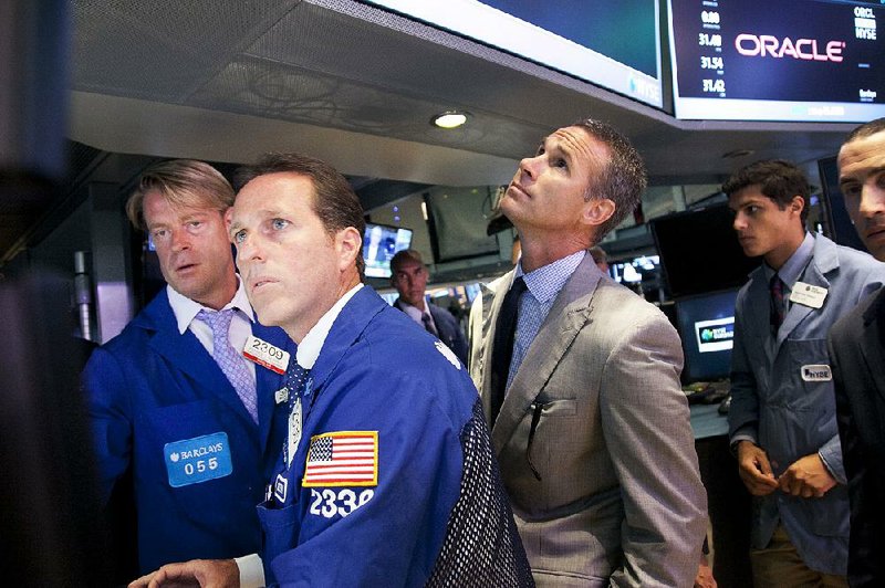 Glenn Carell, second from left, a senior floor official with Barclays Capital, monitors the stock price of Oracle as it opens for trading Monday, July 15, 2013 at the New York Stock Exchange. Oracle Corp., the multinational technology company based in Redwood City, Calif., transferred its listing from Nasdaq to the NYSE. (AP Photo/Mark Lennihan)