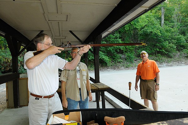 Russ Doran of Rogers, left, shows his unloaded muzzle-loader rifle to Wally Smith, center, and Jerry Oliver on June 12 at the Hobbs State Park-Conservation Area shooting range. All three said another public shooting range is sorely needed in Northwest Arkansas. 