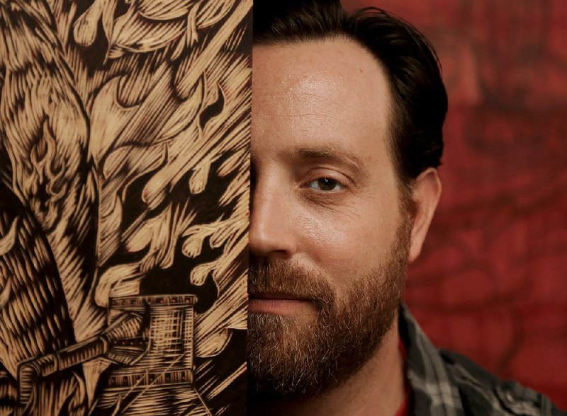 Arkansas Tech University professor of art Neal Harrington poses in his Russellville studio with one of his prints. 