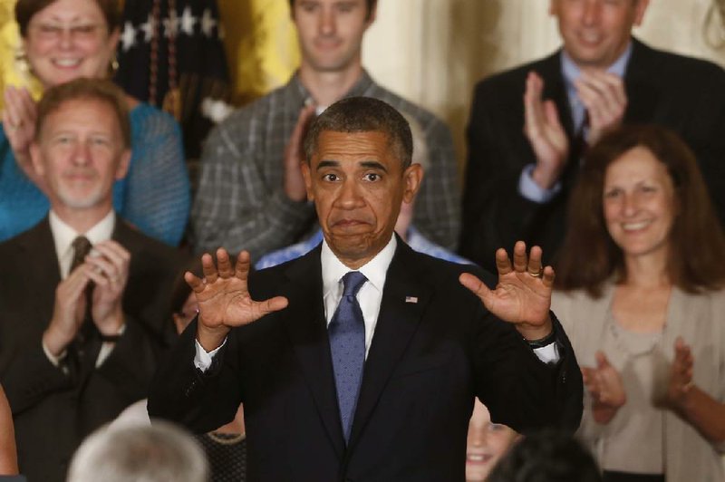 President Barack Obama gestures for audience members to sit down before he speaks about health care reform and the Affordable Care Act in the East Room at the White House in Washington, Thursday, July 18, 2013. (AP Photo/Charles Dharapak)