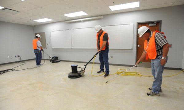Jerry McClendon, right, Jerry Drake, center, and Charles Grubb work to polish and wax the floors Wednesday, July 17, 2013, in a classroom in the the most recently completed portion of the transformation of Fayetteville High School.