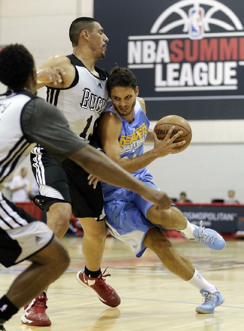 Evan Fournier (right) of the Denver Nuggets drives against Milwaukee Bucks’ Gustavo Ayon during the second quarter of an NBA summer league basketball game in Las Vegas. The NBA’s summer league started years ago with a handful of teams just getting together for a nice little run. Now, 22 teams are in Vegas for the operation, which features for the first time a single-elimination tournament. 