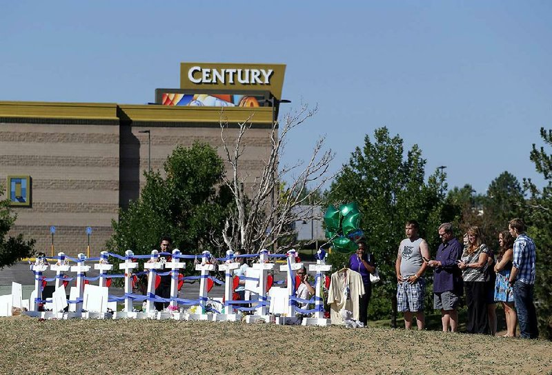 People visit 12 crosses Saturday that were erected on a hill across the street from the Aurora, Colo., theater where 12 people gunned down last year. 