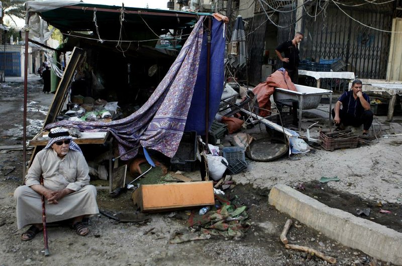 Civilians inspect the aftermath of a car bomb attack  at a convenience store at the Karrada neighborhood of Baghdad, Iraq, Sunday, July 21, 2013.  A coordinated wave of seven car bombs tore through bustling commercial streets Saturday night in Shiite areas of Baghdad, part of a relentless wave of the capital killed and wounded dozens of others Saturday, officials said. (AP Photo/Hadi Mizban)