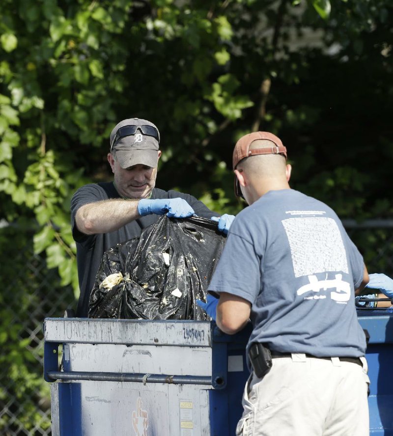 Investigators take out a black trash bag from a dumpster Sunday, July 21, 2013 near where three bodies were recently found in East Cleveland, Ohio. Searchers rummaging through vacant houses in a neighborhood where three female bodies were found wrapped in plastic bags should be prepared to find one or two more victims, a police chief said Sunday. (AP Photo/Tony Dejak)