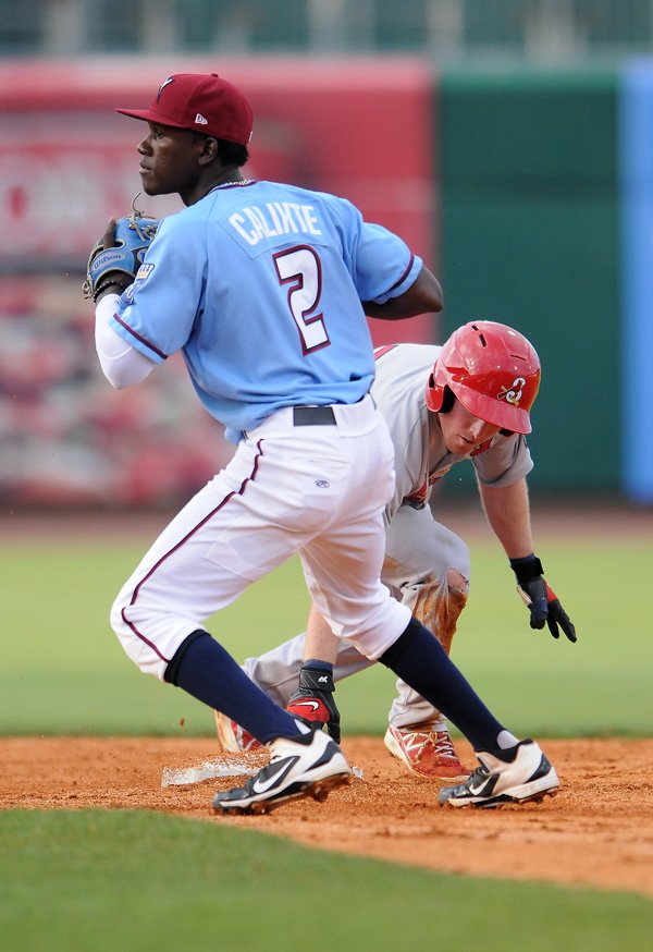 Orlando Calixte, left, of Northwest Arkansas spins around to look at home after making an attempt to tag Springfield’s Mike O'Neill out during Sunday’s game at Arvest Ballpark in Springdale. 