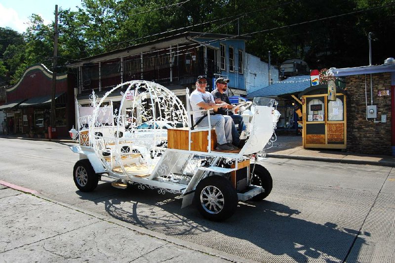 Photo by Bill Bowden -- Todd Mickna, right, and Steve Hobel drive through Eureka Springs Tuesday in a motorized "Cinderella carriage" that the city is trying to ban. Ray Dotson of Springdale, who owns the vehicle, says he has a business license that allows him to operate it in the city, but city aldermen disagree.