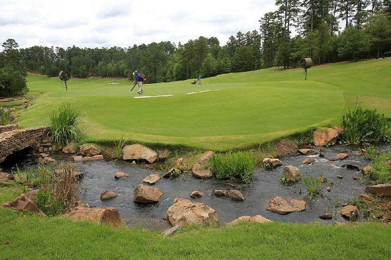 Grounds crew members prepare the 14th green at The Alotian Club in Roland on Thursday in preparation for the 111th Western Amateur tournament, which begins Tuesday. A total of 156 amateurs will compete in the tournament which ends Aug. 4 with semifinal and final rounds of match-play competition. 