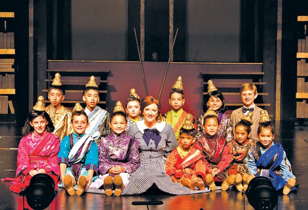 Schoolteacher “Mrs. Anna,” played by Sarah Anders, pauses with the children of the Siamese royal court in the Rogers Little Theater production of “The King and I.” 