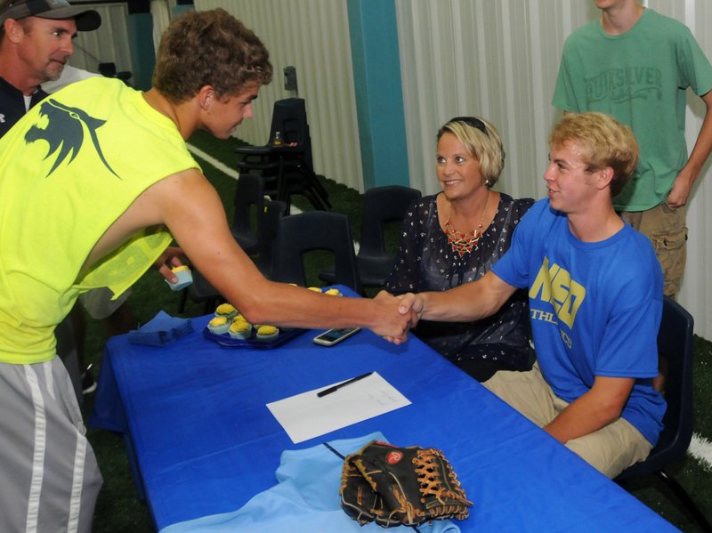 Springdale Har-Ber's Zach Thompson sits next to his mother Jackie Thompson as he is congratulated by one of his friends, Caleb Daniels after he signed his letter of intent to play baseball for Northeastern Oklahoma A&M college (NEO) during a signing ceremony at Har-Ber High school Thursday morning.