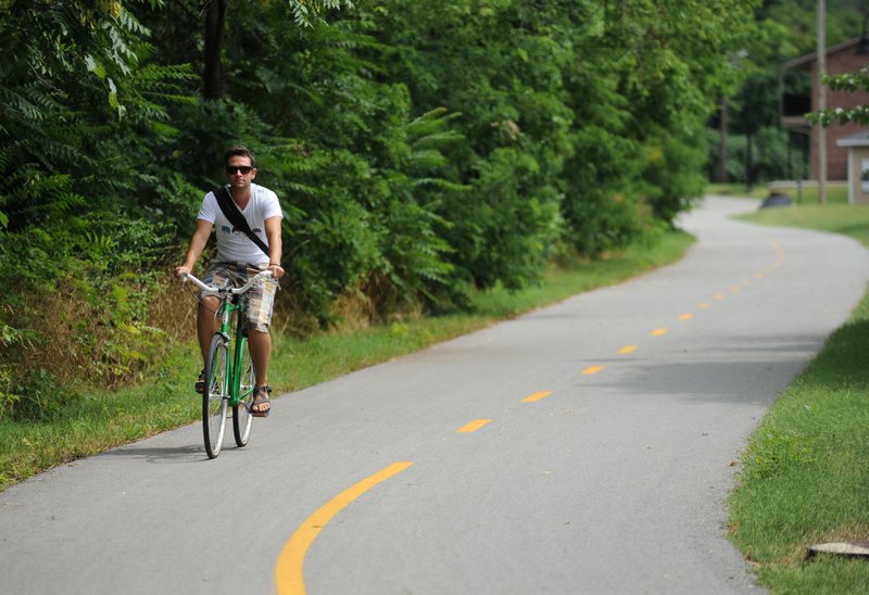 Ryan Klintworth of Fayetteville rides his bicycle Thursday, July 25, 2013, as he makes his way home from his job on the town's square along the Scull Creek Trail. Klintworth rides along the city's trail system and walks his bicycle on the bridge over Interstate 540 along Wedington Drive to get to his home.