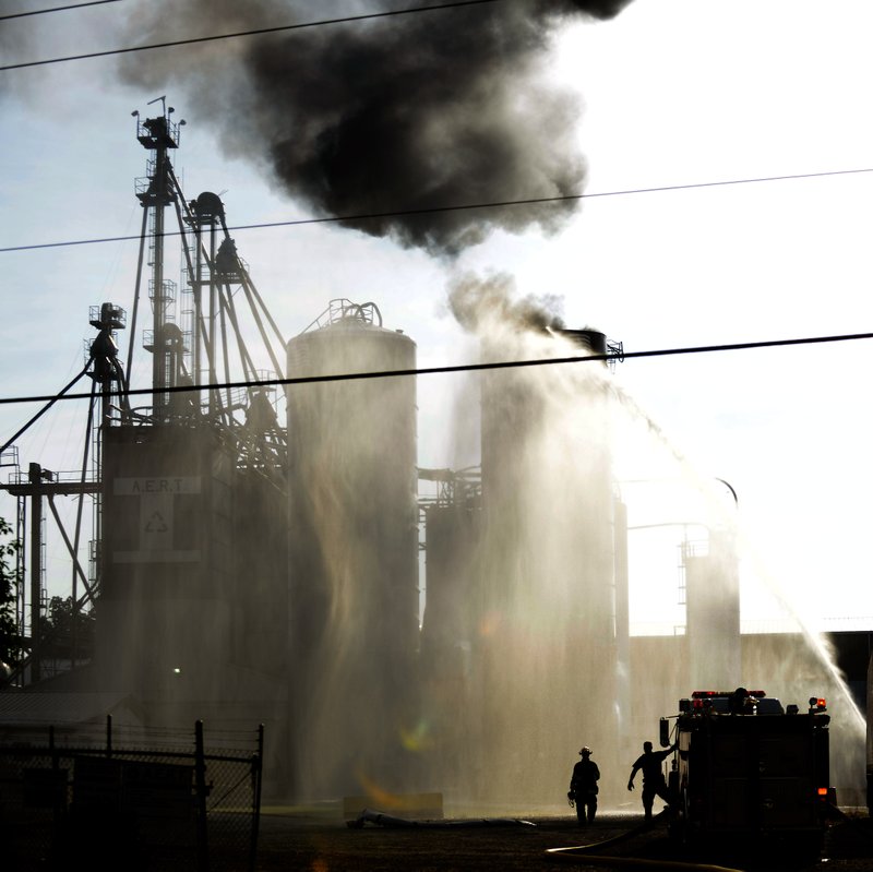 STAFF PHOTO JASON IVESTER
Lowell Firefighters spray water on a burning silo on Thursday, July 25, 2013, following an explosion at the Advanced Environmental Recycling Technologies facility in Lowell. No one was injured from the explosion and police evacuated businesses within 300 meters as a precaution.