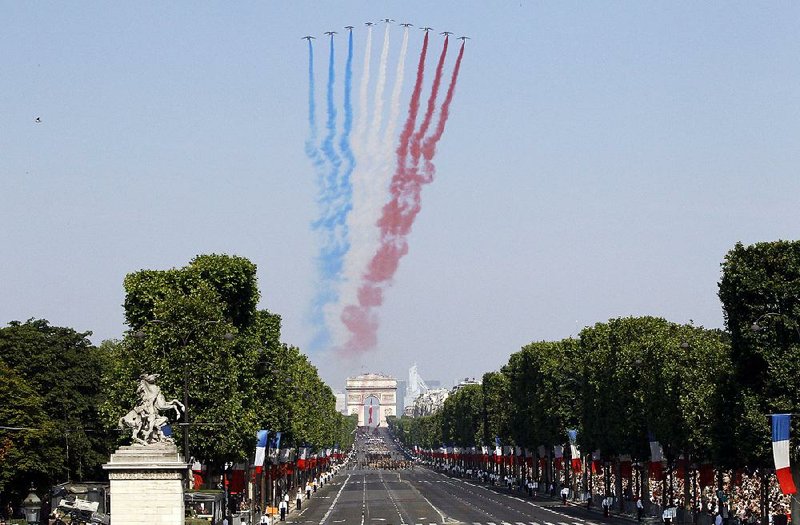 Jets from the Patrouille de France fly over the Champs-Elysees at the start of the Bastille Day parade on July 14. The Arc de Triomphe is in the background. 