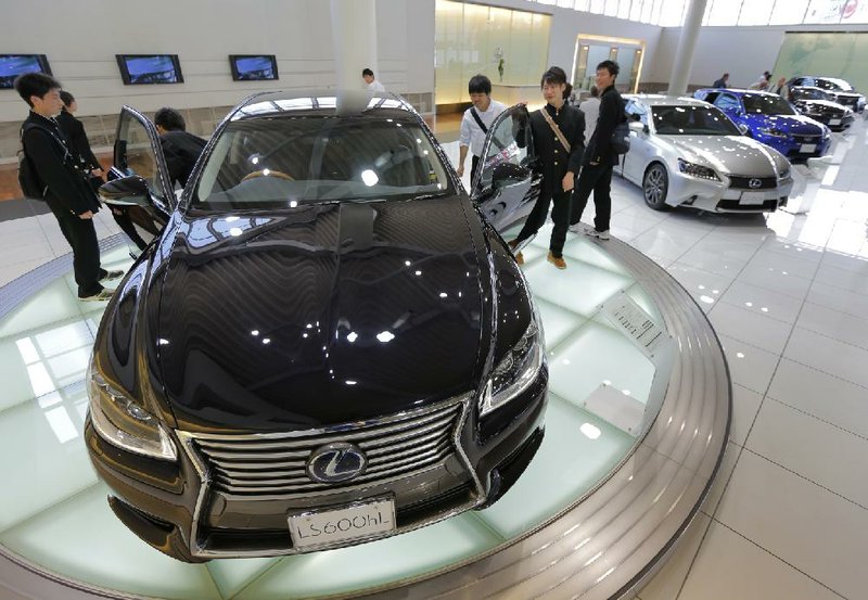 Schoolboys check out a Lexus LS600hL at Toyota Motor Corp.’s showroom in Tokyo in May. Toyota sold 4.91 million cars and trucks in the first half of 2013. 