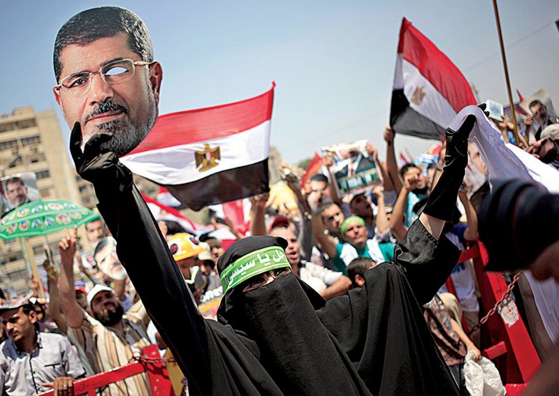 A supporter of ousted Egyptian President Mohammed Morsi holds pictures of the former leader during a protest at Nasr City in Cairo. Political allies of Egypt’s military also held rallies Friday in support of the country’s top general, Abdel-Fattah el-Sissi.