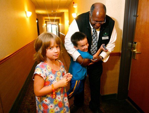 STAFF PHOTO JASON IVESTER
Wingate Hotel staff member John Campbell plays with Landon Lambert, 6, and his sister, Cassie Lambert, 8, on Friday, July 26, 2013, in the hallway of the hotel in Highfill. The hotel hosts rooms for homeless veterans and their families at discounted rates.