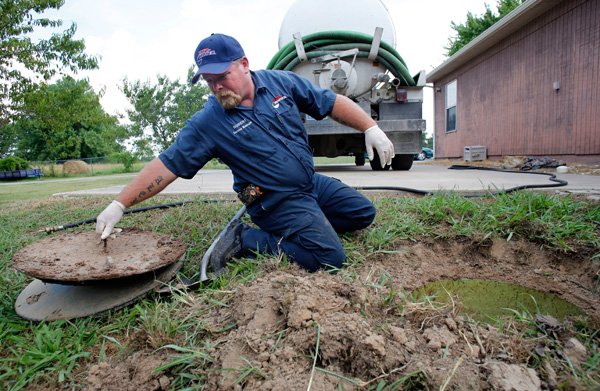 Robert Dunlap, a service manager and septic tank specialist with Roto-Rooter of Northwest Arkansas, removes the lid of a septic tank before pumping out the contents of the tank and cleaning out the interior in Springdale in this Thursday, July 25, 2013, file photo. A septic tank uses natural processes to treat and dispose of wastewater generated in a home or business.