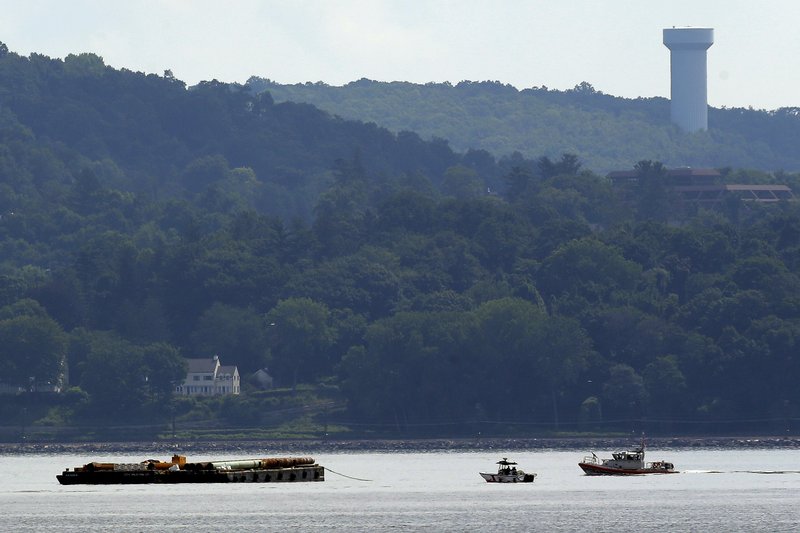 Rescue workers on boats search near a construction barge, left, on the Hudson River in Piermont, N.Y. on Saturday, July 27, 2013, south of the Tappan Zee Bridge after two people fell into the water during a boat crash. One remained missing Sunday after workers found the body of a woman Saturday.