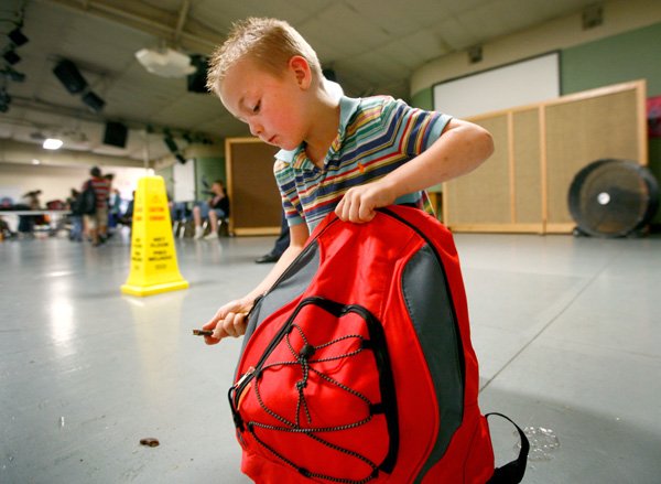 Jackson Martinez, 7, of Rogers zips up his new backpack on Saturday, July 27, 2013, during the 15th annual Backpacks for Kids Day at the Samaritan Community Center in Rogers. Approximately 3000 backpacks filled with grade-appropriate school supplies were distributed to children entering grades K-12. Vouchers for the backpacks were distributed during the month of July through local food pantries.