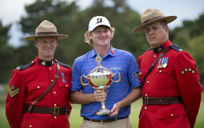 Brandt Snedeker, center, of the United States, poses with Royal Canadian Mounted Police and the championship trophy after winning the Canadian Open golf tournament at Glen Abbey in Oakville, Ontario, Sunday, July 28, 2013. (AP Photo/The Canadian Press, Nathan Denette)