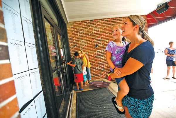 Erin Daniel and daughter Hadley Daniel, 8, look over the lists Friday at R.E. Baker Elementary School in Bentonville to see which class Hadley will be in to start the school year. 