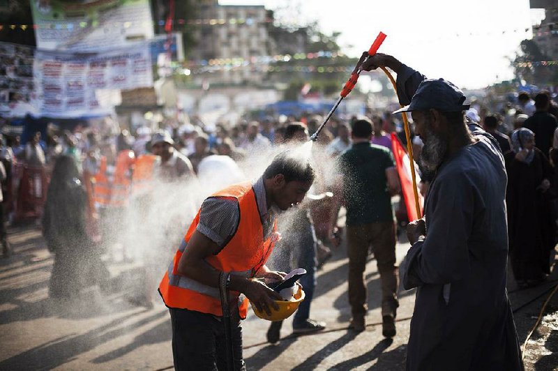 A supporter of Egypt's ousted President Mohammed Morsi cools off with the help of another supporter spraying him with a hose in Nasr City, where protesters have installed a camp and hold daily rallies, in Cairo, Egypt, Monday, July 29, 2013.  Europe's top diplomat urged Egypt's government to reach out to the Muslim Brotherhood as she worked Monday to mediate an end to the country's increasingly bloody crisis, while the mainly Islamist protesters calling for the return of ousted leader Mohammed Morsi massed for more protests. (AP Photo/Manu Brabo)