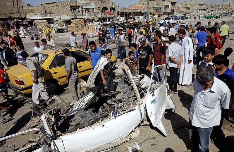 Iraqis inspect the aftermath of a car bomb attack, in the Shiite enclave of Sadr City, Baghdad, Iraq, Monday, July. 29, 2013. A wave of over a dozen car bombings hit central and southern Iraq during morning rush hour on Monday, officials said, killing scores in the latest coordinated attack by insurgents determined to undermine the government. (AP Photo/Karim Kadim)