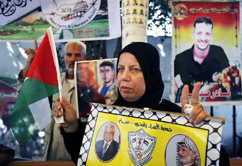 A Palestinian woman holds a placard with Arabic that reads, "prisoners association and ex-prisoners, Hussam," during a sit-in at the International Red Cross in Gaza City, Monday, July 29, 2013. The U.S. on Sunday, June 28, announced the resumption of Israeli-Palestinian talks following years of stalemate, after Israel's Cabinet agreed to release 104 Palestinian prisoners convicted of deadly attacks. The return to direct contacts between the sides gave U.S. Secretary of State John Kerry his first concrete achievement after months of shuttle diplomacy.(AP Photo/Adel Hana)