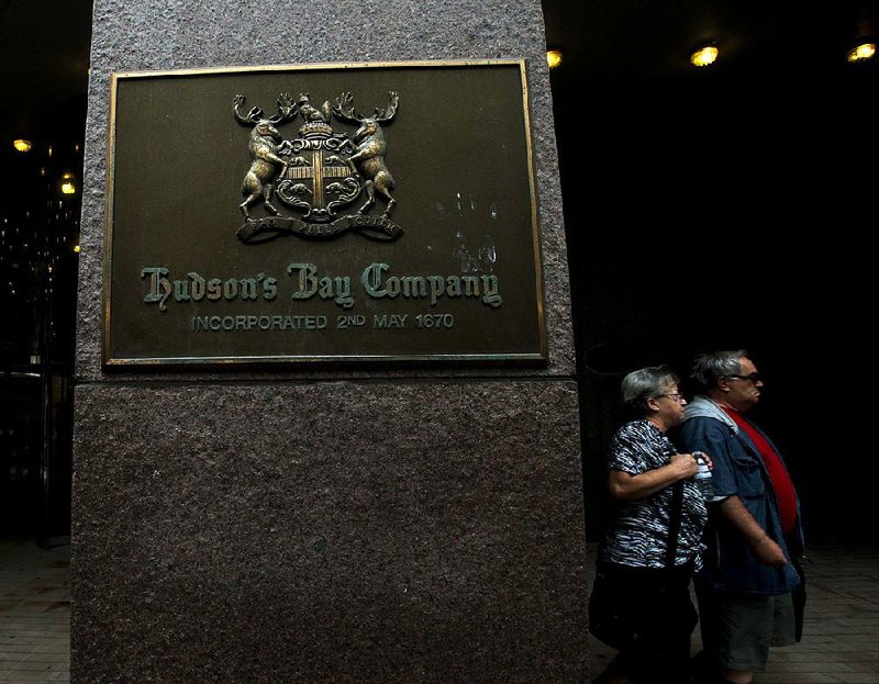 People walk past a Hudson's Bay Co. store sign in Toronto on Monday, July 29, 2013.   Luxury retailer Saks is being purchased by the parent of Lord & Taylor for approximately $2.4 billion.  (AP Photo/THE CANADIAN PRESS, Nathan Denette)