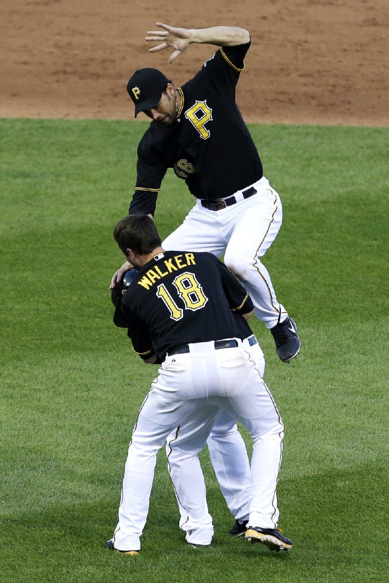 Pittsburgh’s Garrett Jones (top) and Neal Walker (18) celebrate with teammate Alex Presley after Presley’s 11th-inning RBI hit that gave the Pirates a 2-1 victory over St. Louis in the first game of a doubleheader. The Pirates won the second game 6-0. 