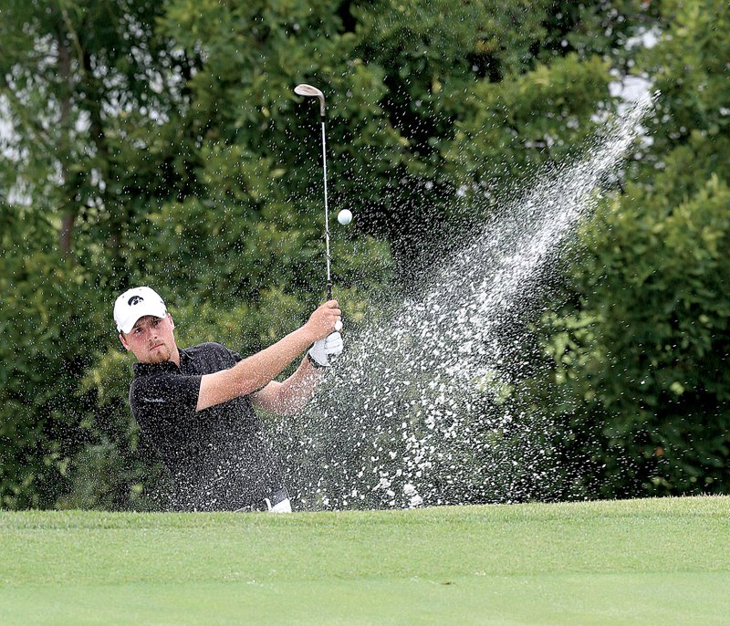 Steven Ihm of Peosta, Iowa, blasts out of the sand just off the 18th green Tuesday during the opening round of the Western Amateur at The Alotian Club in Roland. Ihm shot a 3-over 75 that left him 10 strokes off the lead. 