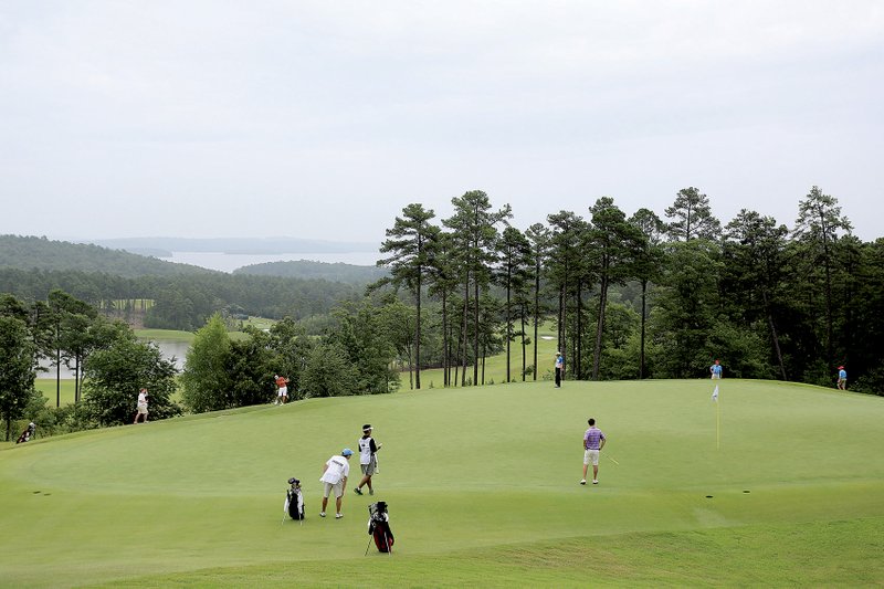 Players surround the 18th green overlooking Lake Maumelle during Tuesday’s opening round of the 111th Western Amateur at The Alotian Club in Roland. The field will be cut to the low 44 scores and ties after today’s second round. 