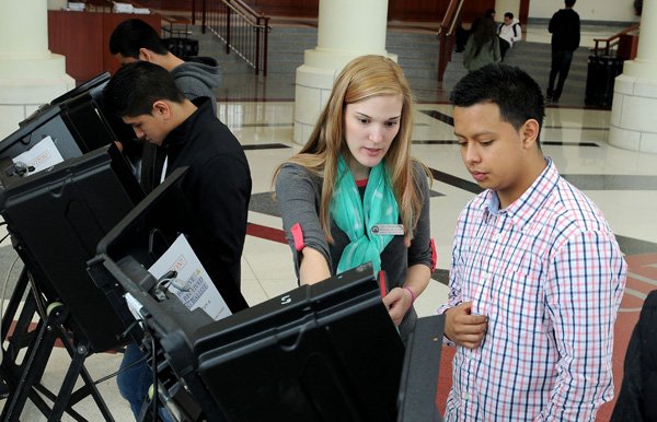 Laura Shepard-Johnson, field technician withe the Washington County Election Commission sets Springdale High School Carlos Arellano, 16, Thursday, April 11, 2013 with an electronic voting machine at the school in Springdale. The comission partenered with the school to show the students what a modern election is like by providing the electronic voting machines, requiring voter registration before election and having students only voted for the grade level.