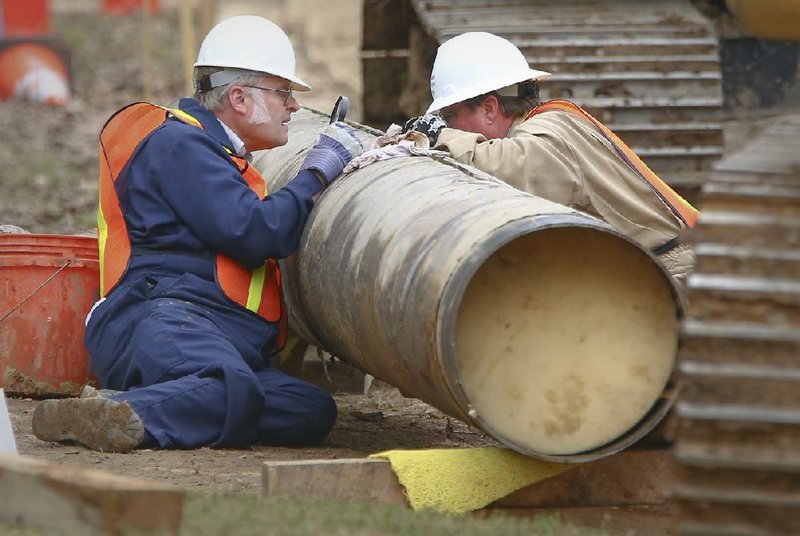 FILE — Exxon Mobil Pipeline workers inspect a split in a section of the Pegasus pipeline in Mayflower on April 15, 2013. 
