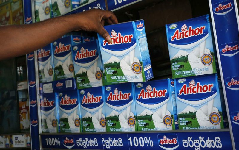 A shop keeper holds a Fonterra product in a store in Colombo, Sri Lanka, on Tuesday. New Zealand’s Fonterra has an annual revenue of $16 billion, the equivalent of 10 percent of the nation’s economy. 