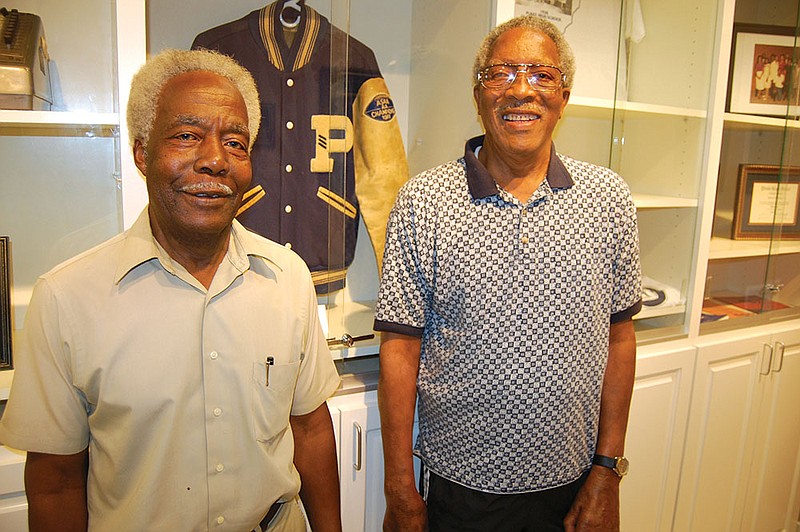 Claubie Beard, left, and Ruben Edmondson, former members of the Peake High School football team, stand before a state-championship school jacket on display in the hallway of the renovated high school building. 