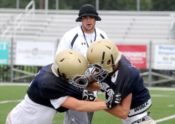 Crosby Tuck, new Shiloh Christian coach, shouts encouragement to players Thursday, Aug. 8, 2013 during drills at practice at Champions Stadium in Springdale. Tuck is a former Saints player who returned this season to coach receivers.