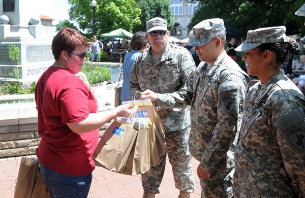 Jennifer Cozens with the Walmart Visitor Center, left, hands out gift bags to members of the 362nd Tactical PsyOp Company, a U.S. Army Reserve unit, before they deploy to eastern Africa Saturday, Aug. 10, 2013, at the Bentonville Square.