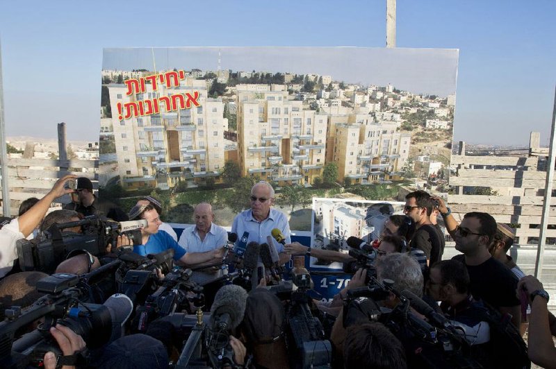 Israeli Minister of Housing and Construction Uri Ariel, center, speaks to journalists during a ceremony to mark the resumption of the construction of housing units in an east Jerusalem neighborhood, Sunday, Aug. 11, 2013. Israel's housing minister on Sunday gave final approval to build nearly 1,200 apartments in Jewish settlements, just three days before Israeli-Palestinian peace talks are to resume in Jerusalem. Hebrew on sign reads "Last Units."(AP Photo/Sebastian Scheiner)