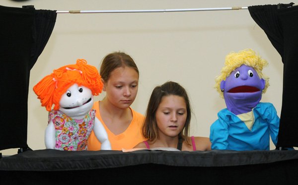 Lindsay Tribble, 12, left, and Halle Bright, 12, practice making their puppets sing to music Saturday, Aug. 10, 2013, at Presbyterian Church of Bella Vista during the church's Puppet Ministry. Kids learn how to use puppets and perform at various events and schools in the area.