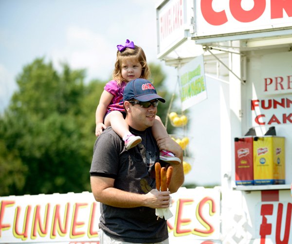 William Lewallen (cq) and his daughter, Madelyn (cq) Lewallen, 2, both of Centerton, look for a seat after purchasing corn dogs on Friday, Aug. 16, 2013, during the Benton County Fair in Bentonville. The 109th annual fair continues through Sunday.