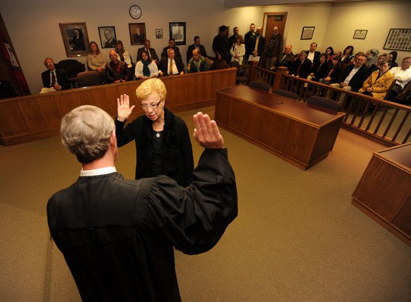 Washington County Judge Marilyn Edwards, center, is sworn in by Washington County Circuit Judge Mark Lindsay on Jan. 2 in Lindsay’s courtroom at the Washington County Courthouse in Fayetteville. “It seems most anything that comes before the Quorum Court is received pretty well until you come to the animal shelter,” Edwards said. 